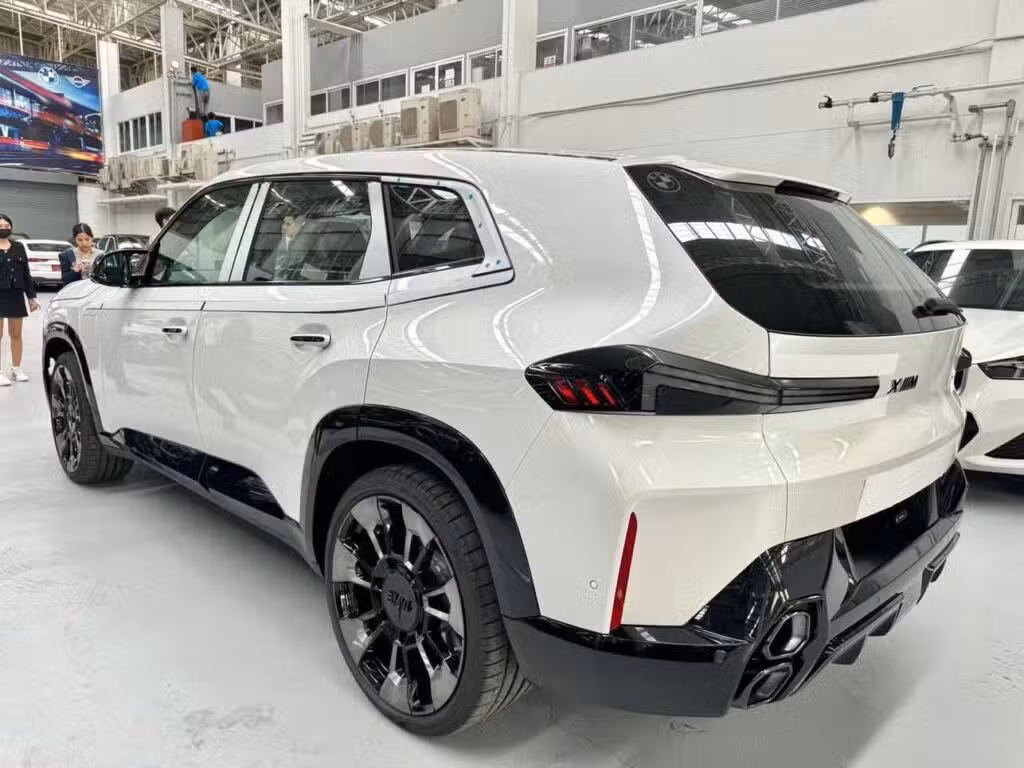 BMW XM 50e rear left three-quarter with wide haunches and black wheels